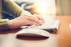Female hands typing text on a wireless keyboard.